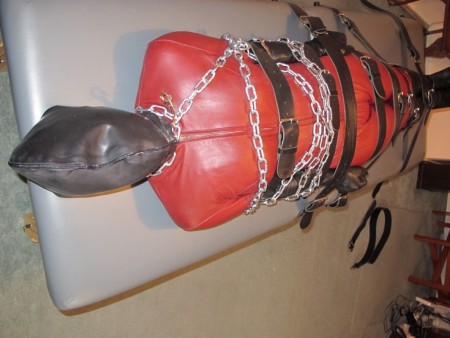 Doublerubber Hooded Catsuited Strapped To The Bondage Table - Double-rubber hooded, and leather catsuited, we watch as karina is tightly strapped down onto the bondage table.  Her upper body is wrapped in steel chains and she struggles to move even the slightest in her tight bondage.
having the outer layer of the hood zipped makes breathing a considerable challenge.

important:  please not that the video goes black from 5m38s to 6m 20s.  This is not a fault.  At the time, I was using a hand-held camera, and to allow me to fasten the second layer of karina's hood (which was very tight) I had to put down the hand-held camera).  The camera output was included in the final version so that you could hear karina's vocals as I completed her bondage.